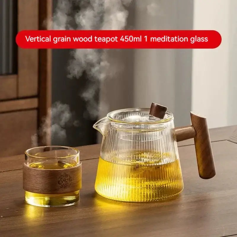 Clear glass decorbites glass teapot with vertical wood grain handle and lid knob filled with steaming golden tea