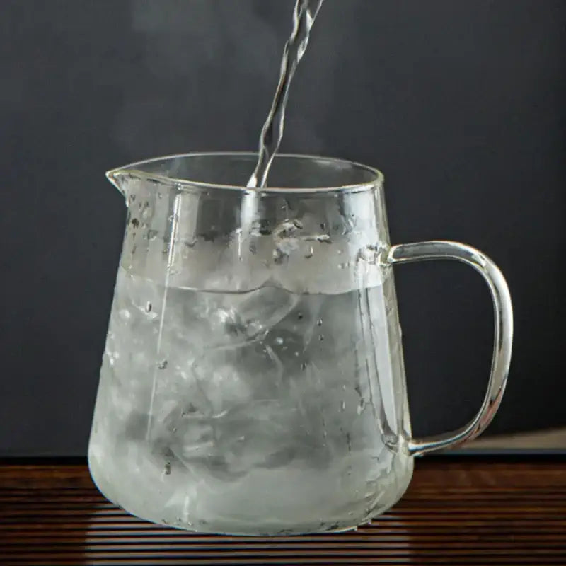 Clear glass decorbites glass teapot with handle spout filled with ice cubes and poured from above for puer tea and coffee