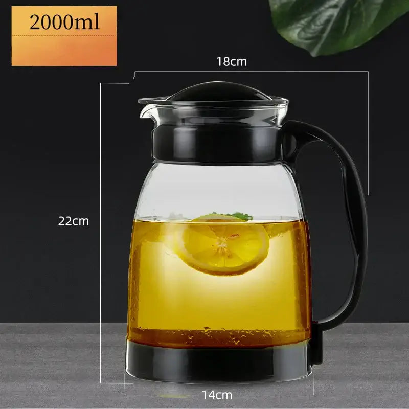 Clear glass teapot with black lid and handle filled with golden liquid and lemon slice from DecorBites glass teapot set