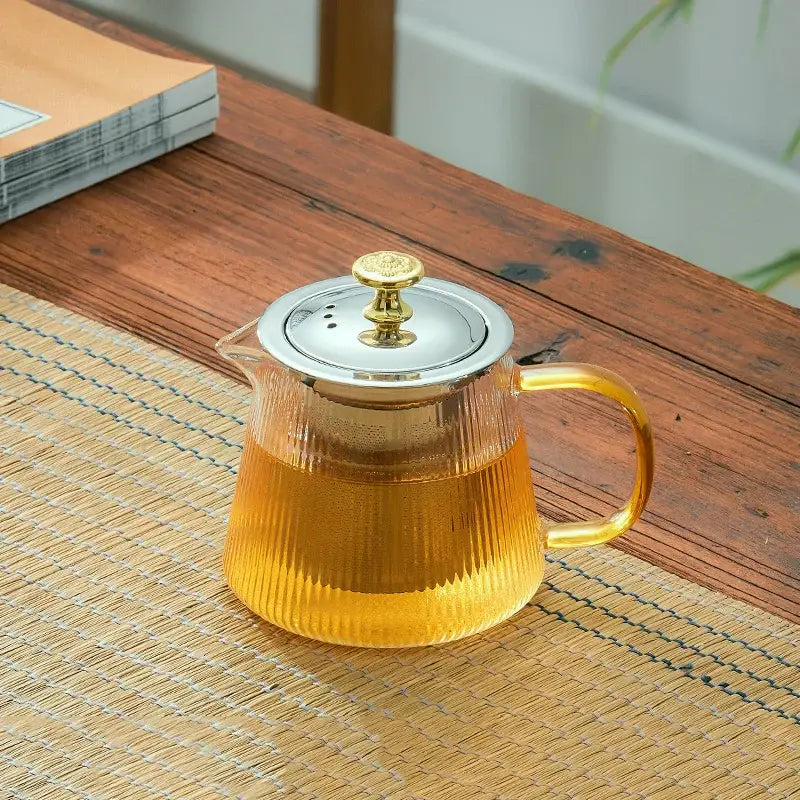 Clear glass teapot puer with vertical ridges and silver lid gold knob holding amber liquid for office and home use