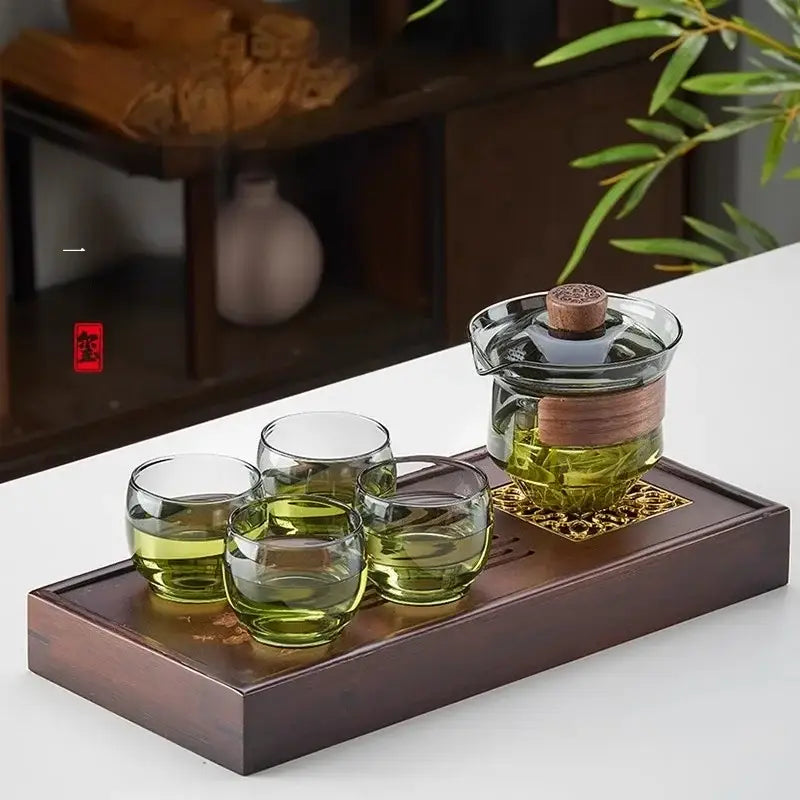 Clear glass teapot set with wooden lid and handle on a bamboo tray filled with green tea by DecorBites glass teapot