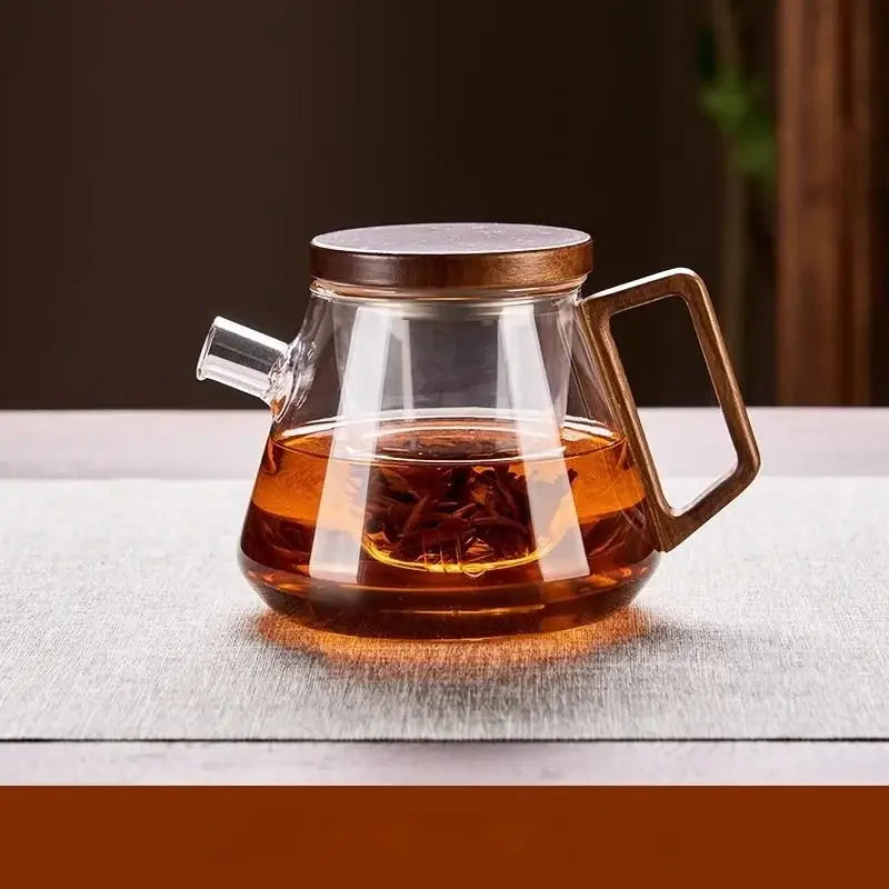 Clear glass teapot set with wooden lid and handle filled with amber tea for kung fu tea and milk rose brewing
