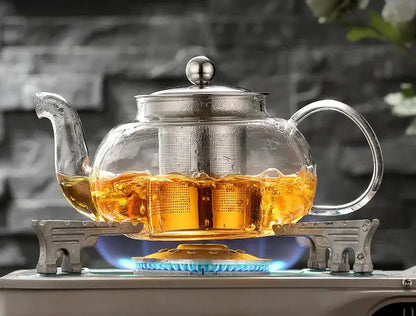 Clear glass teapot set with stainless steel strainer filled with golden tea from decorbites glass teapot collection