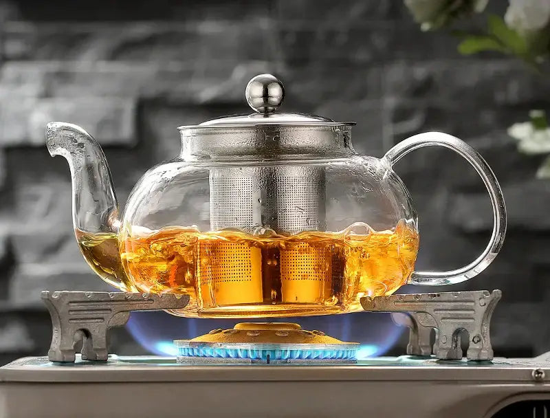 Clear glass teapot set with stainless steel strainer filled with golden tea from decorbites glass teapot collection