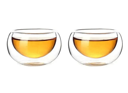 Clear double-walled glass tea cups filled with amber liquid from decorbites glass teapot set with stainless steel strainer