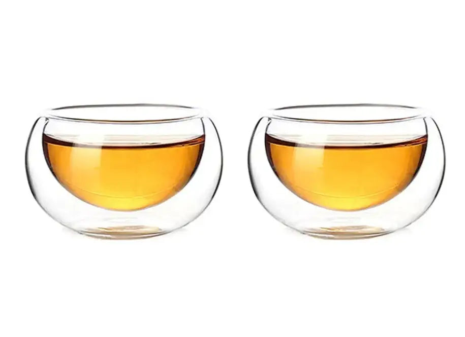 Clear double-walled glass tea cups filled with amber liquid from decorbites glass teapot set with stainless steel strainer