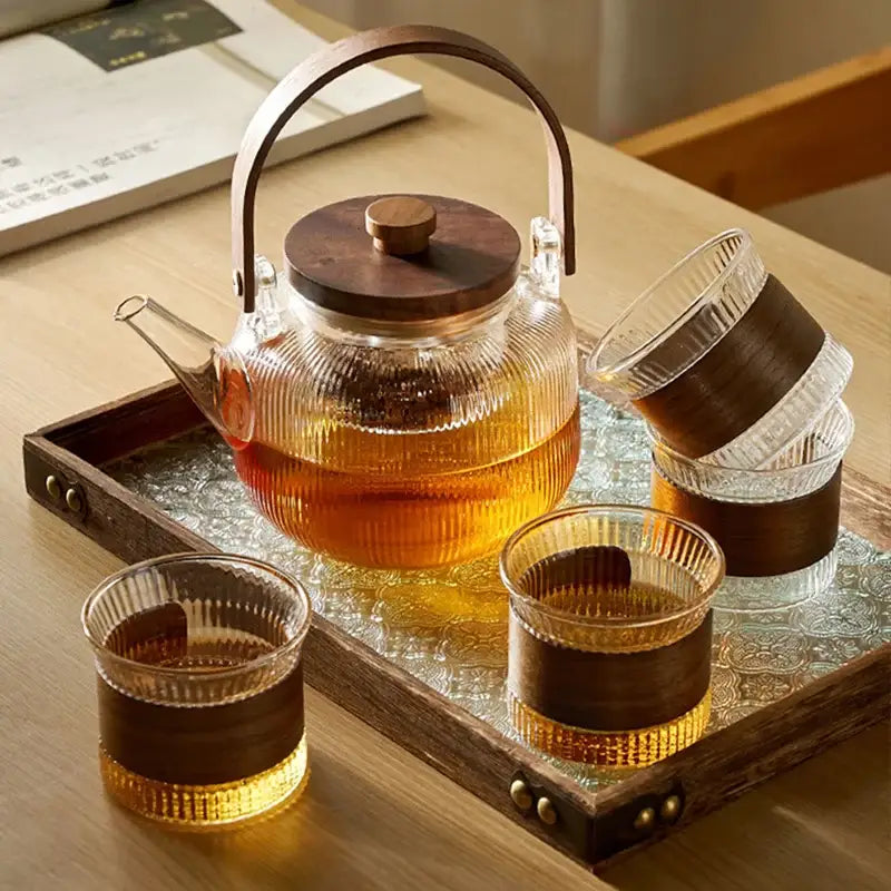Decorbites glass teapot set with clear glass body and wooden handle and lid filled with amber tea