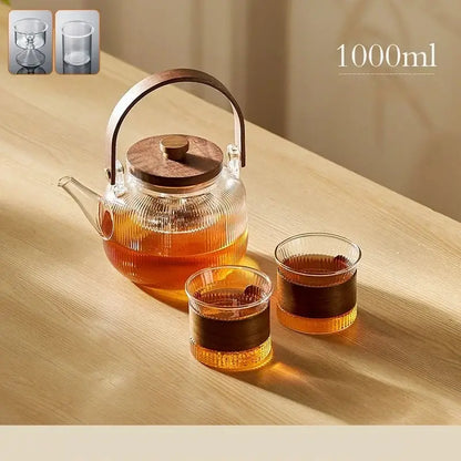 DecorBites glass teapot set with clear glass body and wooden handle and lid filled with amber tea