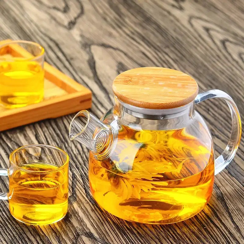 DecorBites glass teapot with bamboo lid and stainless steel rim filled with golden yellow tea for tea brewing
