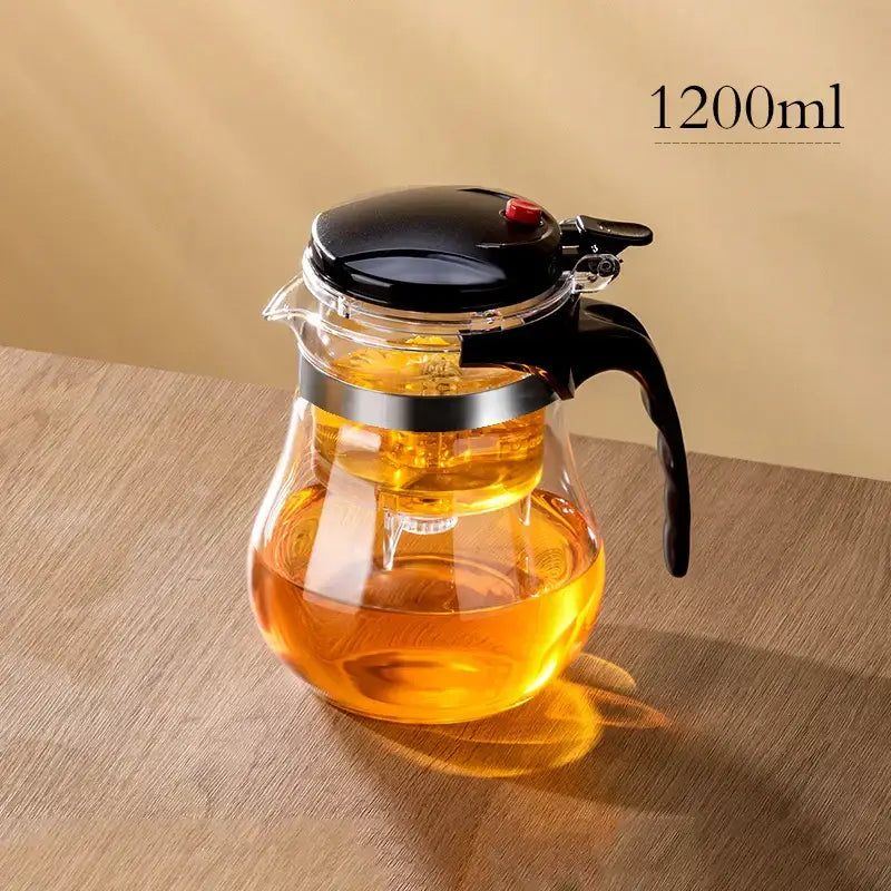Clear glass decorbites glass teapot with black lid handle and silver band featuring one-button filtering system