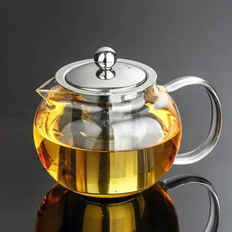 Clear borosilicate glass teapot with stainless steel infuser and lid filled with golden flower tea from DecorBites