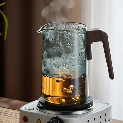Decorbites glass teapot with wood handle filled with steaming golden tea heat resistant filtering kettle