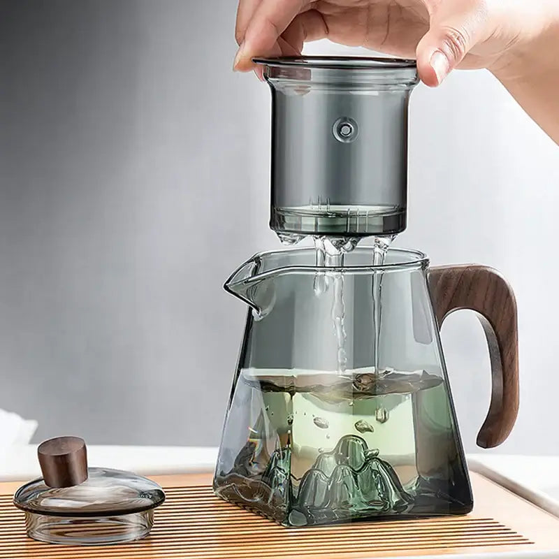 A sleek dark-tinted decorbites glass teapot with a wooden handle and matching lid for heat resistant kung fu tea brewing