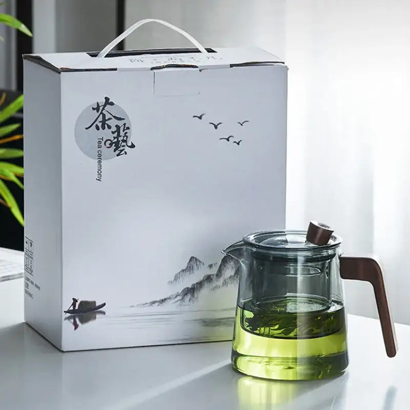 A clear DecorBites glass teapot with wood handle and lid steeping green tea leaves for Chinese tea ceremony use