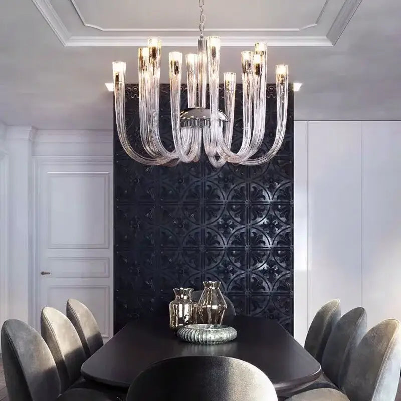 A modern decorbites glass tube dining chandelier with clear glass arms and a metallic central fixture above the table