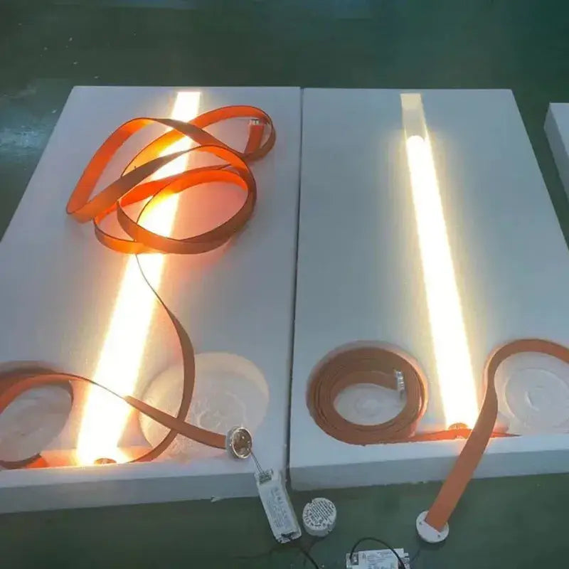 Orange flexible LED strip light with warm glow displayed on white foam boards for decorbites glass tube pendant lamp
