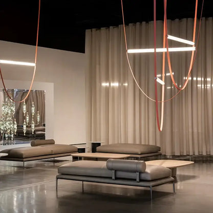 Modern taupe leather lounge sofa with minimalist metal frame and cylindrical backrest near decorbites glass tube pendant light