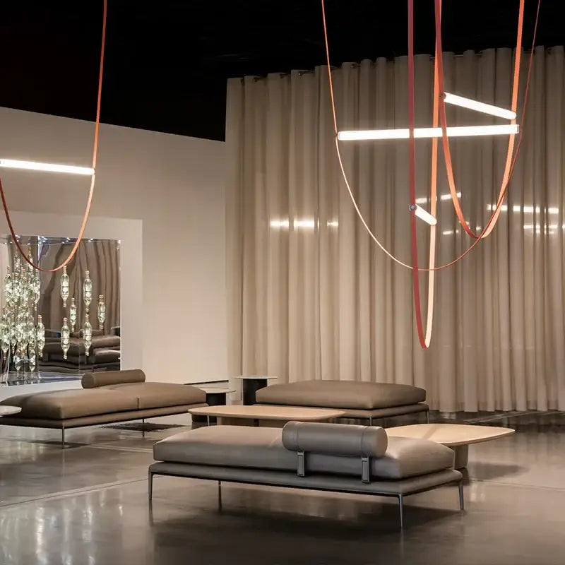 Modern taupe leather lounge sofa with minimalist metal frame and cylindrical backrest near decorbites glass tube pendant light