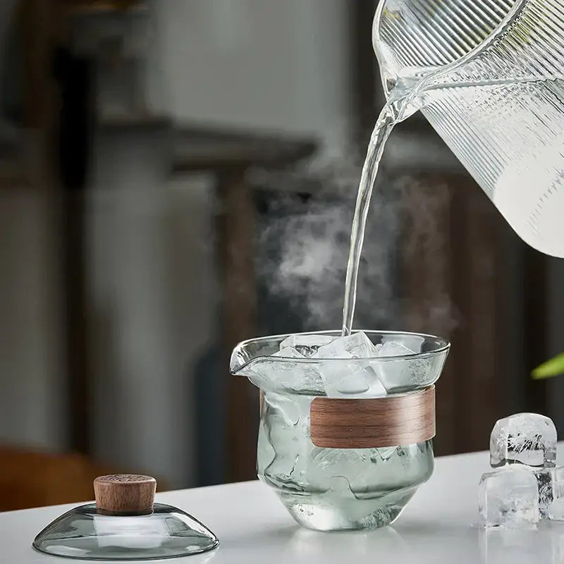Clear glass decorbites glass tureen teapot with wooden band and cork lid filled from matching ribbed pitcher for kung fu tea set