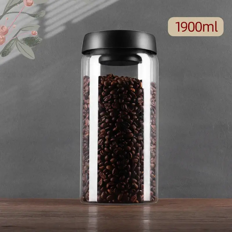 Clear glass vacuum sealed decorbites jar with black lid holding dark roasted coffee beans for kitchen storage
