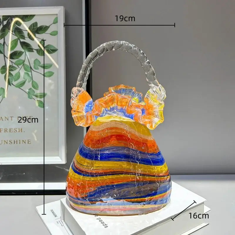 A vibrant decorbites glass vase basket handbag with swirling orange yellow and blue stripes and a clear twisted handle