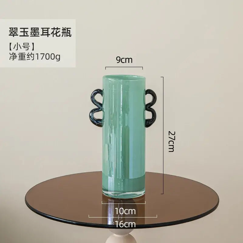 A sleek mint-green decorbites glass vase with black loop handles for flower arrangement and home decoration