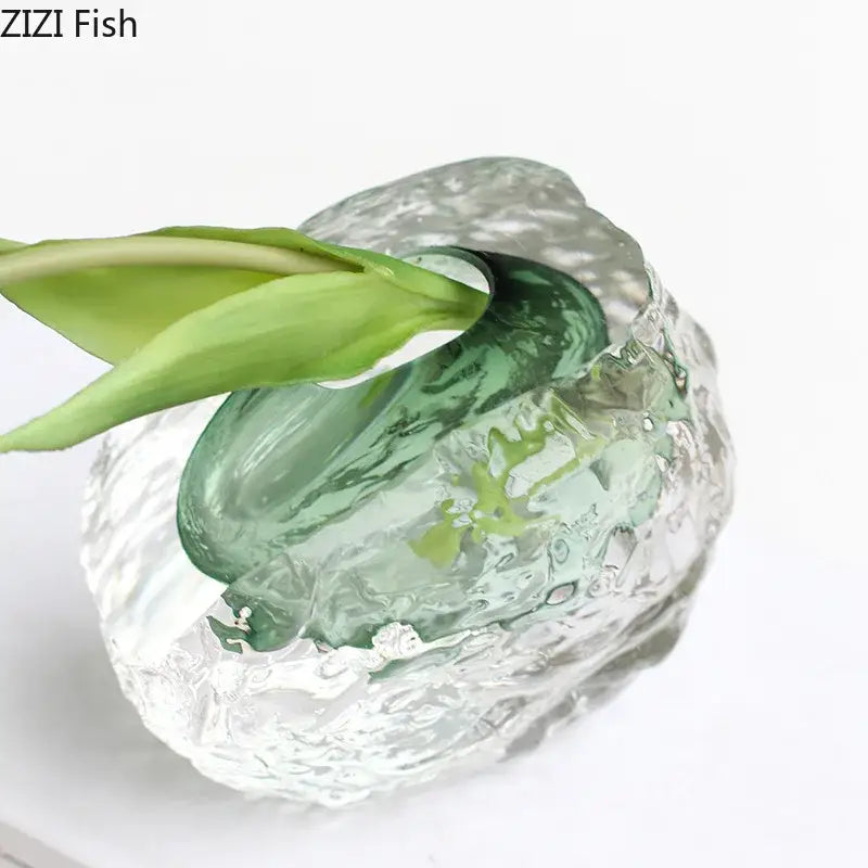 A translucent green DecorBites glass vase with elegant wrinkle design holds a single emerging leaf for room decor