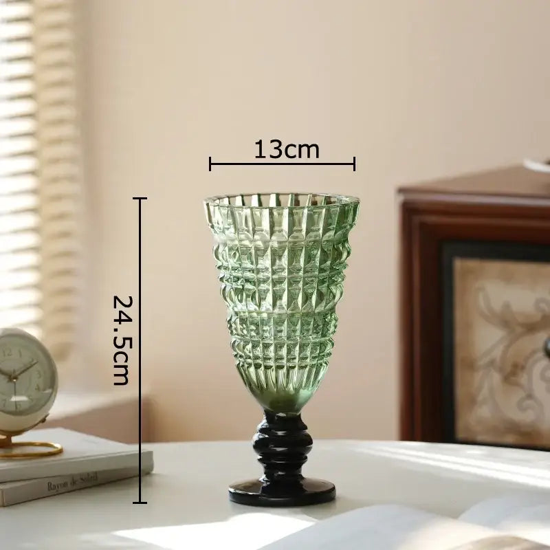 A tall emerald green decorbites glass vase with a faceted texture and black pedestal base for hydroponics and decor