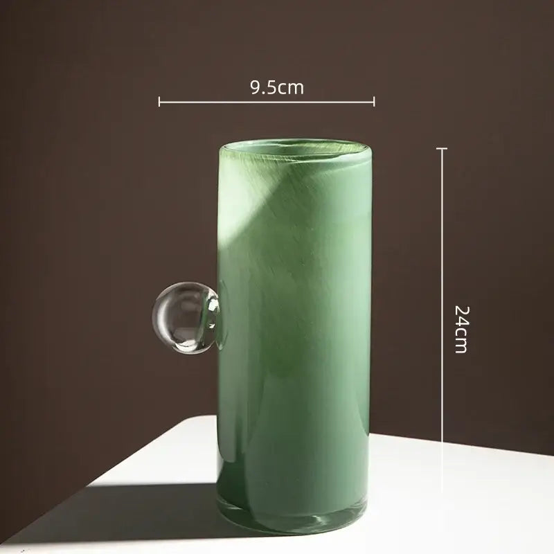 A translucent sage green decorbites glass vase with a clear geometric sphere handle for flowers and accessories