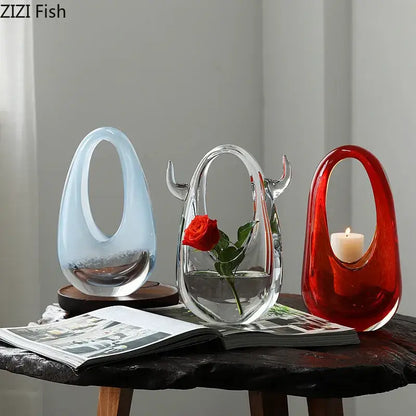 Three decorbites glass vases with organic shapes in light blue, clear with rose, and red holding a candle for elegant decoration