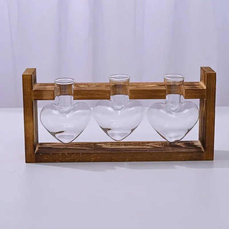 Set of three clear glass vase heart hydroponic plant holders nestled in a rustic wooden frame by decorbites
