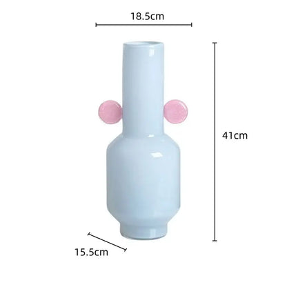 A sleek light blue ceramic decorbites glass vase with two pink spherical handles for floral arrangement accessory
