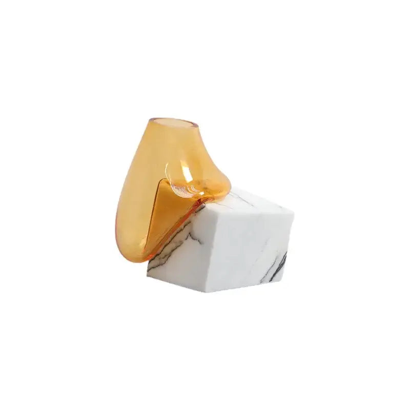 Translucent amber decorbites glass vase with sleek curved design resting on white marble base for elegant decor