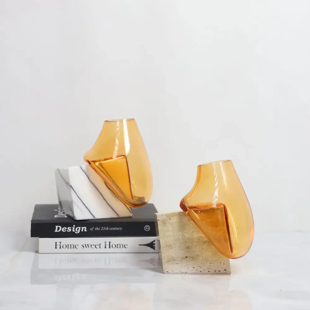 Two amber-colored decorbites glass vases with modern abstract design and marble base for elegant home décor and floral arrangements