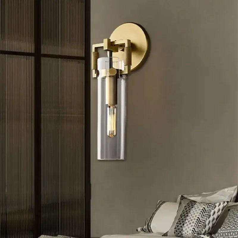 Gold-toned decorbites glass wall lamp with clear glass cylinder and exposed filament bulb for industrial style decor