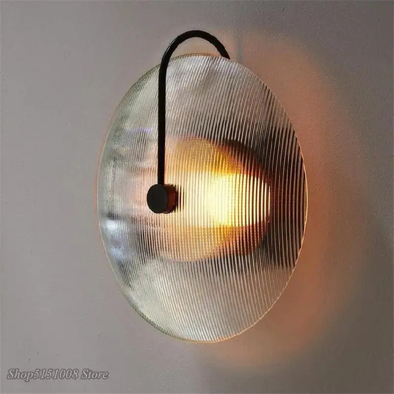 A black metal decorbites glass wall lamp with a circular ribbed glass shade for minimalist home decor lighting
