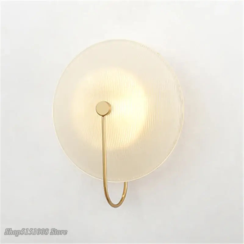 Minimalist gold-toned decorbites glass wall lamp with frosted ribbed glass shade and curved metal arm for home decor