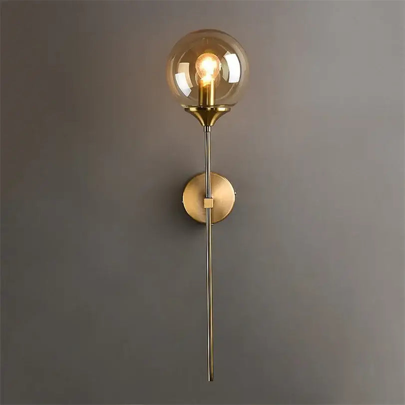 Gold-toned DecorBites glass wall lamp with spherical glass globe and exposed filament bulb for bedroom lighting