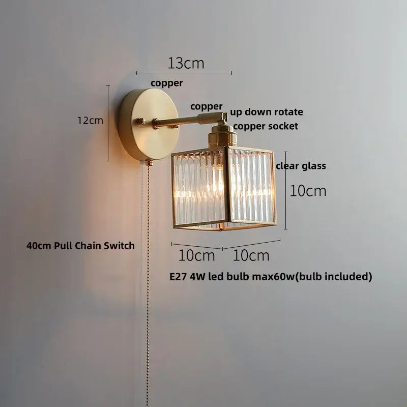 A brass-finished copper decorbites glass wall light sconce with clear glass cube and vertical ribbed panels for modern lighting