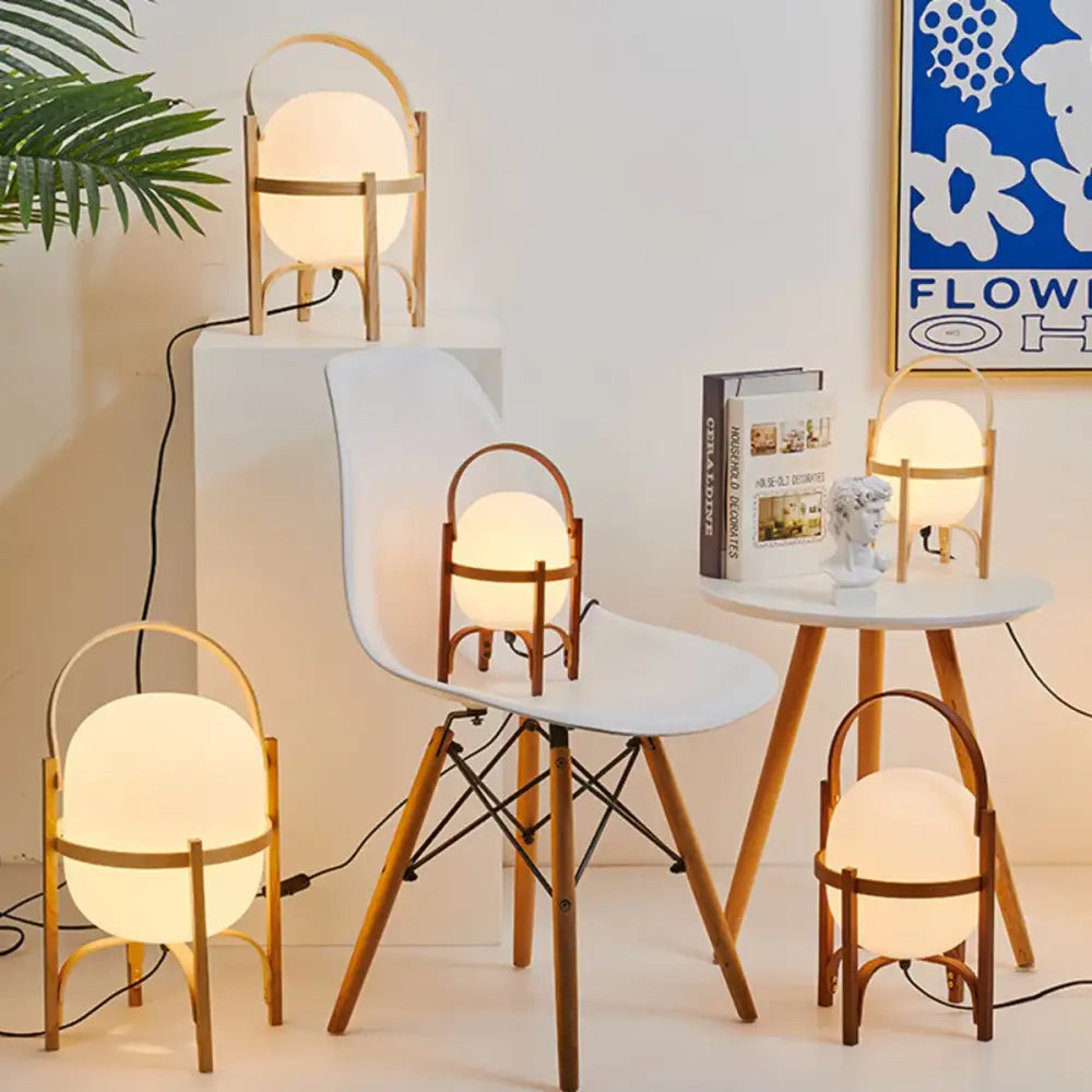 Warmly glowing decorbites glass and wood metal table lamp with spherical shade and minimalist curved wooden handle