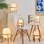 Warmly glowing decorbites glass and wood metal table lamp with spherical shade and minimalist curved wooden handle