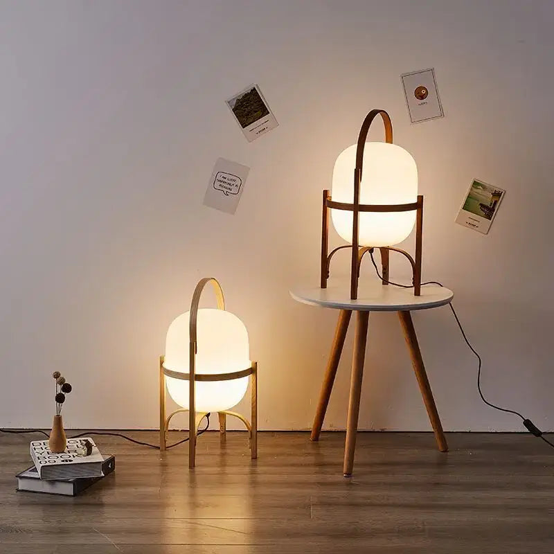 Warmly glowing decorbites glass metal table lamp with frosted oval shade and minimalist wood metal table frame