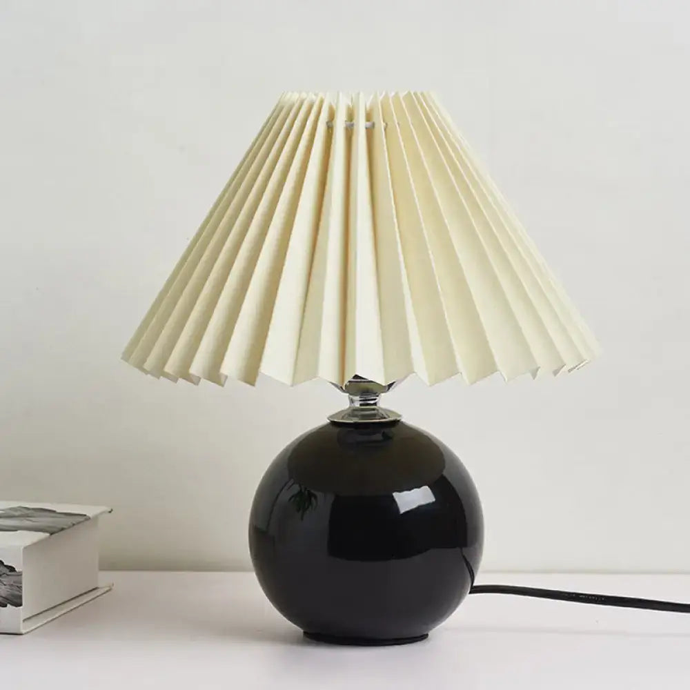 Black glossy ceramic bedside table lamp with cream pleated fabric shade for modern nightstand lighting