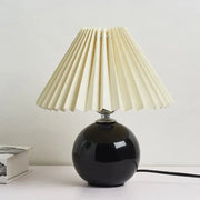 Black glossy ceramic bedside table lamp with cream pleated fabric shade for modern nightstand lighting