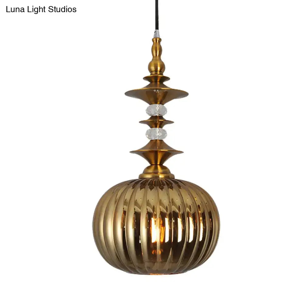 Gold-toned glass pendant light with ribbed spherical shade and ornate brass accents in chrome copper gold finish for dining room