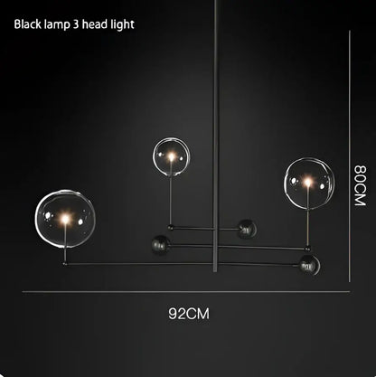 Black metal chandelier featuring three spherical gold glass bubble lights ideal for dining room decor