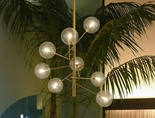 Modern brass chandelier featuring clear glass globe bulbs in a gold glass bubble design for dining room decor