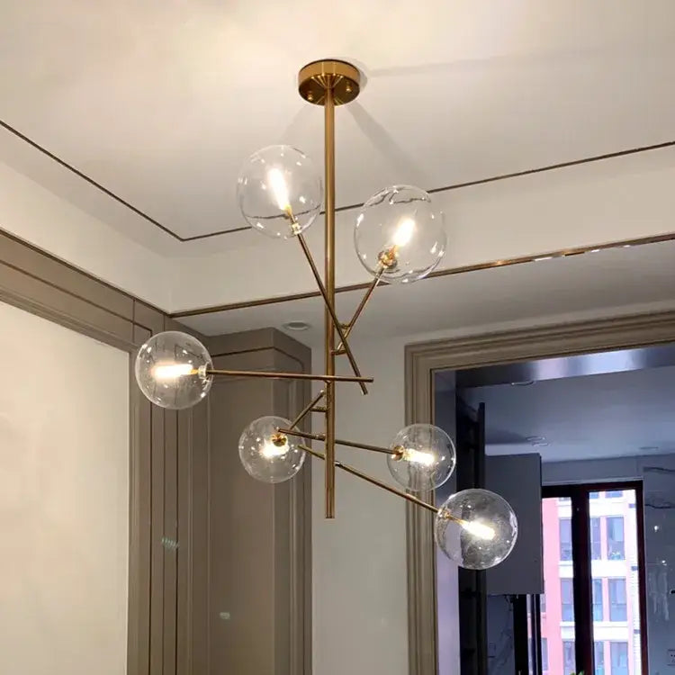 Modern brass chandelier with six clear glass globe bulbs featuring gold glass bubble design for dining room decor
