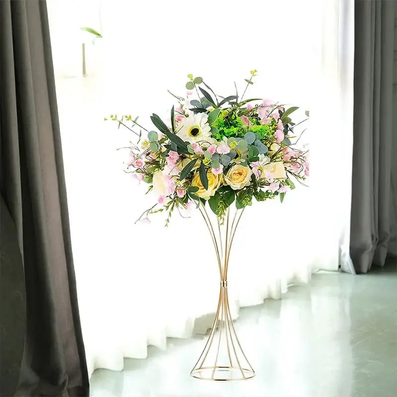 A gold-toned iron flower vase by DecorBites holds artificial pink, yellow, and white flowers with green foliage