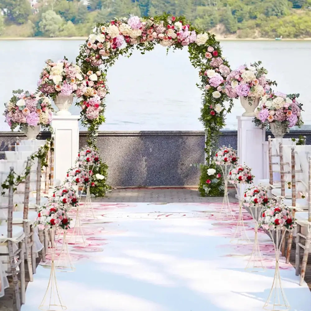 A lush floral archway featuring pink, white, and red roses on decorbites gold metal trumpet flower stand vase
